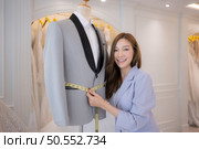 Asian fashion designers make sure the groom’s outfit is absolutely accurate and ready for the bride and groom to try on. Стоковое фото, агентство Ingram Publishing / Фотобанк Лори