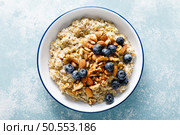 Oatmeal porridge with blueberry, almonds, walnuts, flax seeds, sesame and chia. Healthy vegetarian food for breakfast, top down view. Стоковое фото, агентство Ingram Publishing / Фотобанк Лори