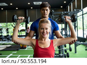 Young couples work out at the gym to strengthen the body. Each person recommends exercise for each other and encourage each other while exercising. Стоковое фото, агентство Ingram Publishing / Фотобанк Лори