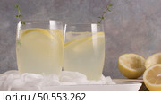 Cold lemonade or alcoholic cocktail with lemon, rosemary and ice in glass glasses on a light background. Стоковое фото, агентство Ingram Publishing / Фотобанк Лори