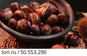 Roasted chestnuts on a rustic wooden table with autumn leaves in the background. Стоковое фото, агентство Ingram Publishing / Фотобанк Лори