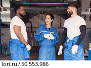 Portrait of smiling team of mechanics in auto repair shop,  Talking one another while standing under car. Стоковое фото, агентство Ingram Publishing / Фотобанк Лори