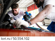 Car mechanic working in an auto repair shop, inspecting the operation of the car’s air conditioner and refrigerant. Стоковое фото, агентство Ingram Publishing / Фотобанк Лори
