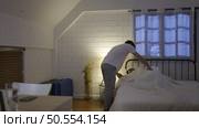 A young Asian man working overtime at home covers the blanket for his sleeping wife on the bed. prior to continuing work. Стоковое фото, агентство Ingram Publishing / Фотобанк Лори