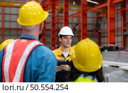 Supervisor and group of factory workers wearing hard hats meeting brief together before starting the day’s work. Стоковое фото, агентство Ingram Publishing / Фотобанк Лори
