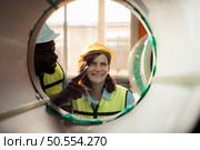 A team of young men and woman working in a warehouse storing rolls of metal sheets. Inspecting the metal sheet rolls stored in the warehouse to be imported onto the metal sheet production line. Стоковое фото, агентство Ingram Publishing / Фотобанк Лори
