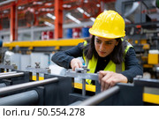 A female factory technician use a wrench to inspect the conveyor belt of the metal sheet production machine. Стоковое фото, агентство Ingram Publishing / Фотобанк Лори