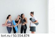 A group of female and male athletes stood and chatted amicably in the studio before beginning with the yoga class. Стоковое фото, агентство Ingram Publishing / Фотобанк Лори