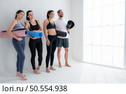 A group of female and male athletes stood and chatted amicably in the studio before beginning with the yoga class. Стоковое фото, агентство Ingram Publishing / Фотобанк Лори