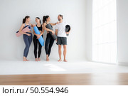 A group of female and male athletes stood and chatted amicably in the studio before beginning with the yoga class. Стоковое фото, агентство Ingram Publishing / Фотобанк Лори