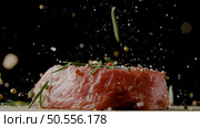 Close-up of falling salt and pepper on raw beef steaks on table, freeze motion. Стоковое фото, агентство Ingram Publishing / Фотобанк Лори