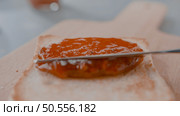 spreading tasty peach jam on bread slice in kitchen. Стоковое фото, агентство Ingram Publishing / Фотобанк Лори