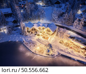Aerial view of illuminated houses in fairy village in snow, forest, Jasna lake, street lights at winter night. Top view of alpine countryside, snowy pine trees at dusk. Kranjska Gora, Slovenia. Стоковое фото, агентство Ingram Publishing / Фотобанк Лори