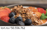 Yogurt with baked granola and berries in small bowl strawberries blueberries. Granola baked with nuts and honey for little sweetness. Slide from left. Стоковое фото, агентство Ingram Publishing / Фотобанк Лори
