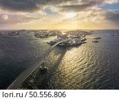 Aerial view of bridge, snowy rocks, islands with rorbu, sea, water, mountains, orange sky with clouds at sunset in winter. Beautiful landscape. Top view of road. Henningsvaer, Lofoten islands, Norway. Стоковое фото, агентство Ingram Publishing / Фотобанк Лори