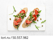 Tuna caper toasts with arugula, tomatoes and whole rye bread, top view. Стоковое фото, агентство Ingram Publishing / Фотобанк Лори