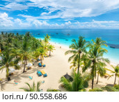 Aerial view of white sandy beach with palm trees, sunbeds, umbrellas, yachts, boats, blue ocean, sky with clouds at sunset. Summer in Kendwa, Zanzibar island. Tropical landscape. Clear sea. Top view. Стоковое фото, агентство Ingram Publishing / Фотобанк Лори