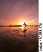 Hydrofoil rider gliding over the water with his board in one of the canals of the Ria de Aveiro in Portugal during sunset. Стоковое фото, агентство Ingram Publishing / Фотобанк Лори
