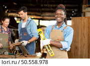 Portrait of carpenter female worker standing in front of colleague in workshop. Стоковое фото, агентство Ingram Publishing / Фотобанк Лори