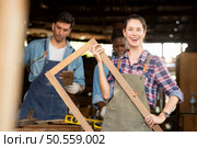 Portrait of carpenter female worker standing in front of colleague in workshop, Eyesight is utilized to ensure accuracy. Стоковое фото, агентство Ingram Publishing / Фотобанк Лори