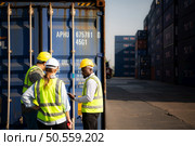 Group of workers in an empty container storage yard, The condition of the old container is being assessed to determine whether it requires maintenance for usage. Стоковое фото, агентство Ingram Publishing / Фотобанк Лори