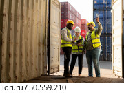 Group of workers in an empty container storage yard, The condition of the old container is being assessed to determine whether it requires maintenance for usage. Стоковое фото, агентство Ingram Publishing / Фотобанк Лори