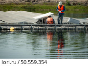 Both of technicians are currently evaluating and repairing the transmission terminals for electricity generated by solar energy in a floating solar power system. Стоковое фото, агентство Ingram Publishing / Фотобанк Лори