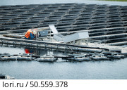 Technician currently evaluating and repairing the transmission terminals for electricity generated by solar energy in a floating solar power system. Стоковое фото, агентство Ingram Publishing / Фотобанк Лори