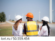 Back view of group engineers and architects on construction site with wind turbines in background. Стоковое фото, агентство Ingram Publishing / Фотобанк Лори
