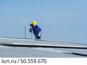 A new technician trainee working on solar panels with a fear of heights. Стоковое фото, агентство Ingram Publishing / Фотобанк Лори
