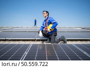 Technician repairing solar panels take off his hat and rest in the scorching sun on a factory roof covered with solar panels to receive solar energy. Стоковое фото, агентство Ingram Publishing / Фотобанк Лори
