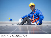 Technician repairing solar panels rest in the scorching sun on a factory roof covered with solar panels to receive solar energy. Стоковое фото, агентство Ingram Publishing / Фотобанк Лори