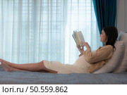Pregnant woman reading a stories to her unborn child in the living room at home. Стоковое фото, агентство Ingram Publishing / Фотобанк Лори