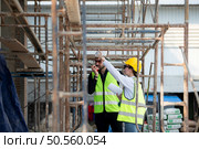 Engineer and architect working on the construction site, double-checking plans and process. Стоковое фото, агентство Ingram Publishing / Фотобанк Лори
