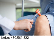A doctor uses a reflex hammer to evaluate a patient’s knee joint. Стоковое фото, агентство Ingram Publishing / Фотобанк Лори