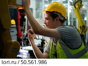 Technician who maintains a small robot arm the operation of a small robot arm used in industry is being repaired. Стоковое фото, агентство Ingram Publishing / Фотобанк Лори