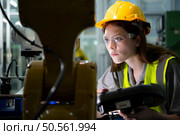 Female technician who maintains a small robot arm the operation of a small robot arm used in industry is being repaired. Стоковое фото, агентство Ingram Publishing / Фотобанк Лори