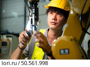 Technician who maintains a small robot arm the operation of a small robot arm used in industry is being repaired. Стоковое фото, агентство Ingram Publishing / Фотобанк Лори
