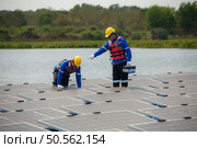 Photovoltaic engineers work on floating photovoltaics. Inspect and repair the solar panel equipment floating on the water. Стоковое фото, агентство Ingram Publishing / Фотобанк Лори
