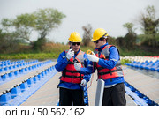 Photovoltaic engineers work on floating photovoltaics. Inspect and repair the solar panel equipment floating on the water. Стоковое фото, агентство Ingram Publishing / Фотобанк Лори