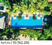 Aerial view of swimming pool, sunbeds and umbrellas, green palms, sandy beach in luxury resort at sunset in summer. Nungwi, Zanzibar island. Top drone view. Tropical landscape. Exotic. Sea coast. Стоковое фото, агентство Ingram Publishing / Фотобанк Лори