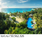 Aerial view of palms, pool, bungalow, sandy beach, umbrellas, yachts, boats, blue ocean, sky with clouds at sunset. Summer vacation in Kendwa, Zanzibar island. Tropical landscape. Clear sea. Top view. Стоковое фото, агентство Ingram Publishing / Фотобанк Лори
