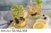 Summer healthy cocktails of citrus infused waters, lemonades or mojitos, with lime lemon orange blueberries and mint, diet detox beverages, in glasses on light background. Стоковое фото, агентство Ingram Publishing / Фотобанк Лори