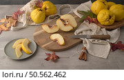 Ripe yellow quinces or queen apple fruits and sliced quince halves with seeds in craft cork plates on black rustic background. Стоковое фото, агентство Ingram Publishing / Фотобанк Лори