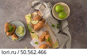 Cod dumplings, or "bolinhos de bacalhau" and parsley leaves and lemons on wooden cutting board in a kitchen counter top. Стоковое фото, агентство Ingram Publishing / Фотобанк Лори