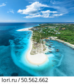 Aerial view of the boats on tropical sea coast with white sandy beach on summer sunny day. Travel in Kendwa, Zanzibar island. Landscape with boats, clear blue water, sky, clouds, palms. Top drone view. Стоковое фото, агентство Ingram Publishing / Фотобанк Лори