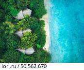 Aerial view of green palms, bungalows, white sandy beach, ocean with waves at sunset in summer. Top view of wooden houses, sea with azure water, trees. Luxury resort in Zanzibar. Tropical background. Стоковое фото, агентство Ingram Publishing / Фотобанк Лори