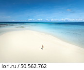 Aerial view of alone young woman on the sandbank in ocean, white sand, blue sea during low tide at sunny summer day in Nakupenda, Zanzibar island. Top view of girl, sand spit, water, sky with clouds. Стоковое фото, агентство Ingram Publishing / Фотобанк Лори
