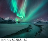 Northern Lights, snowy mountains, sandy beach, creek at starry winter night. Lofoten islands, Norway. Amazing Aurora borealis. Sky with polar lights. Landscape with aurora, sea, stream, rocks in snow. Стоковое фото, агентство Ingram Publishing / Фотобанк Лори