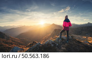 Young woman on mountain peak and beautiful mountain valley in haze at colorful sunset in autumn. Dolomites, Italy. Sporty girl, mountain ridges in fog, orange grass, trees, golden sun in fall. Hiking. Стоковое фото, агентство Ingram Publishing / Фотобанк Лори